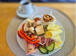 Auf dem Bild ist ein Frühstücksteller mit Aufschnitt nd Gemüse abgebildet.