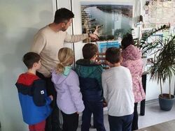 Auf dem Bild sind Fünf Kinder und Bürgermeister Jochen Engel zu sehen, der die Einrichtung seines Büros erklärt.