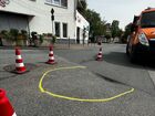 Das Bild zeigt eine Vertiefung im Asphalt an der Kreuzung Groß-Gerauer - Nauheimer Straße in Trebur. EIne gelbe Umkreisung markiert die Schadstelle. Drum herum sind Pylone zu sehen welche die Stelle absichern.