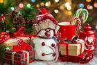 Das Bild zeigt ein weihnachtliches Motiv mit kleinen hübsch eingepackten Geschenken und einem kleinen Schneemann vor einem Weihnachtsbaum