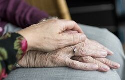 Auf dem Bild sind Hände einer älteren Person zu sehen, die von einer jüngeren Hand gehalten werden.