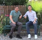 Auf dem Bild sind auf einer Bank im Freien sitzend zu sehen: Andreas Holzmann im grünen kurzärmeligen Hemd und Bürgermeister Jochen Engel