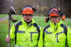 Auf dem Bild sind 2 Bauhofsmitarbeiter zusehen, die nach dem Mähen voller Hundekot sind