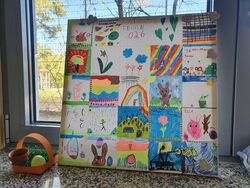 Es zeigt eine Leinwand die in Quadrate aufgeteilt und separat von Kindern mit Ostermotiven bemalt wurde.