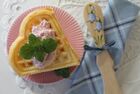 Waffelstück in Herzform auf rosa Teller. Auf der Waffel befindet sich eine Kugel Eis mit Minze.