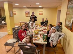 Auf dem bild sind zwölf geflüchtete Kinder aus der Ukraine zu sehen, die zusammen an einem Weihnachtstisch sitzen