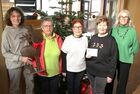 Das Foto zeigt 5 Frauen die vor einem festlich geschmückten Weihnachtsbaum stehen und einen Briefumschlag hochhalten