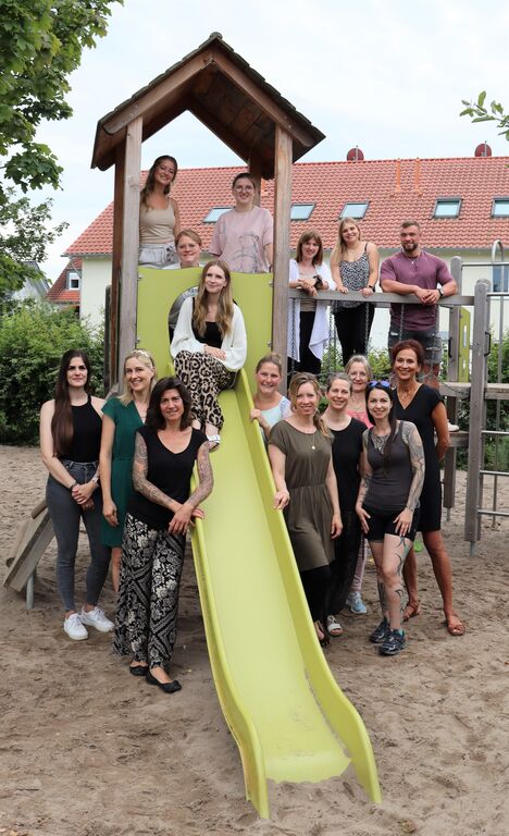 Das Team des Kinder- und Familienzentrums 'Phantásien' auf und neben einer gelben Rutsche